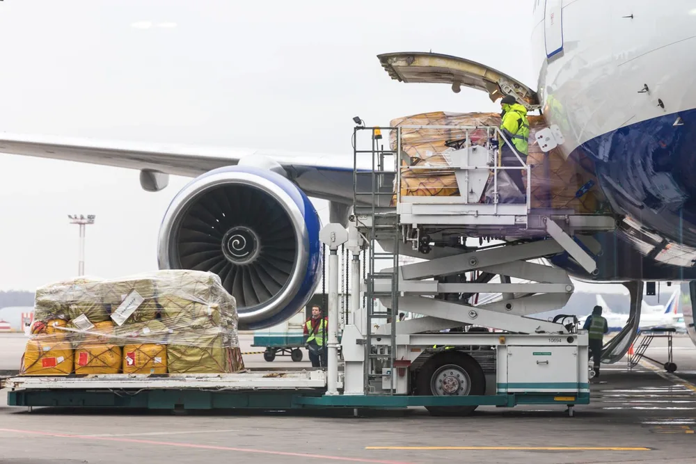 Luftfracht-Paletten werden über einen Hochhubwagen in ein Frachtflugzeug geladen.