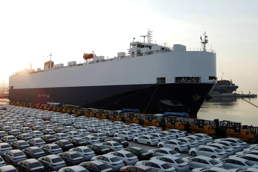 Autotransportschiff am Kai, davor Neufahrzeuge zur Verladung aufgereiht.